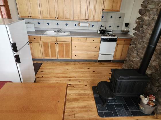 A cabin kitchen with a gas range and wood stove