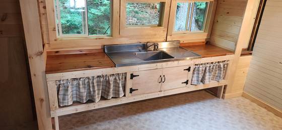 A rebuilt cabin kitchen with a view into the trees