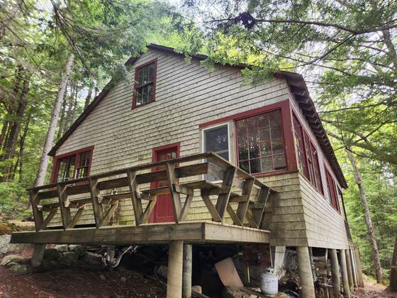 A cabin standing on posts above the hillside