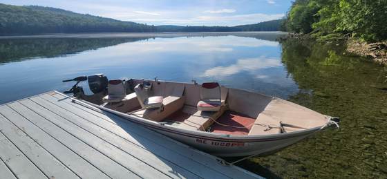 A boat tied up at the dock on a mirror-calm morning